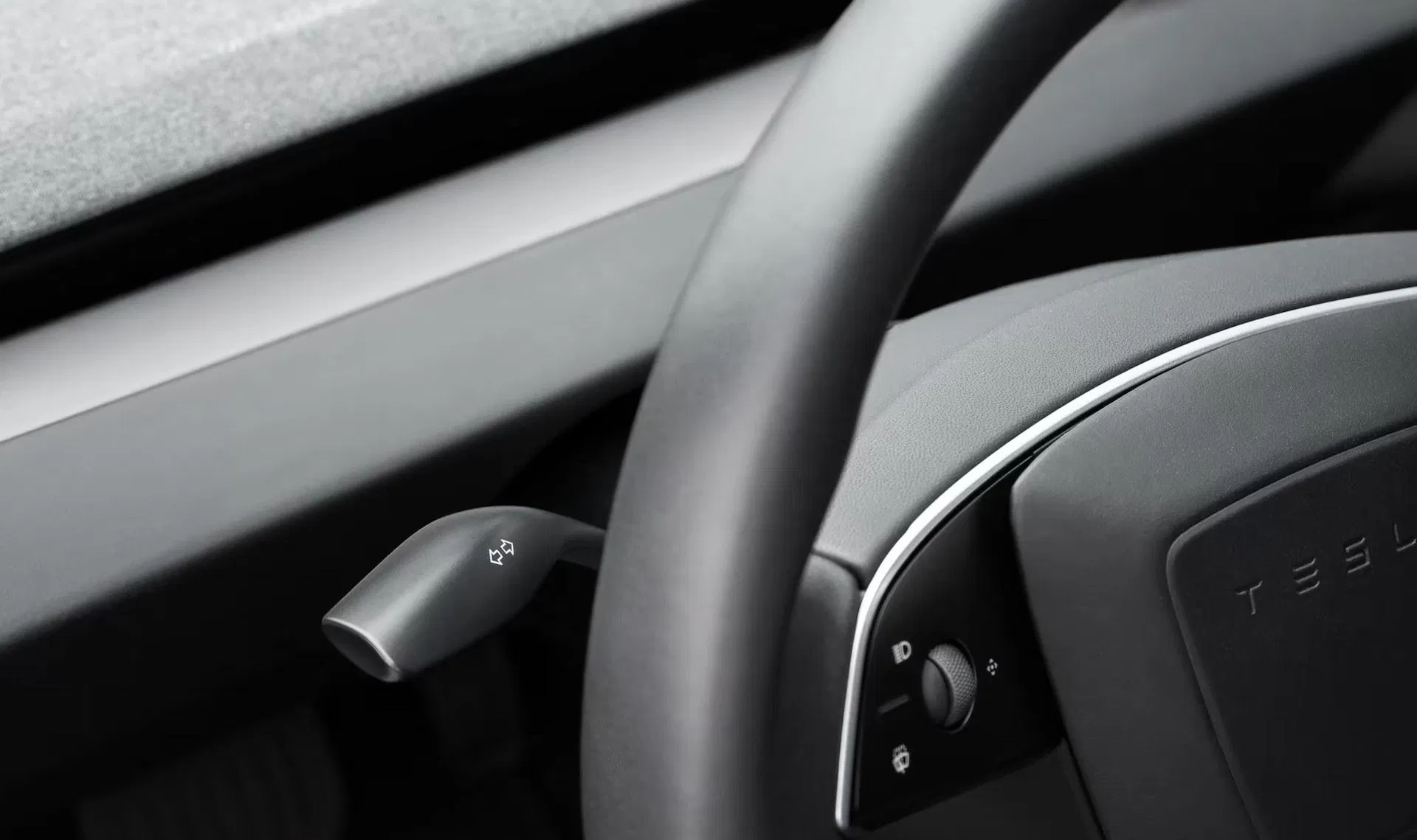 Tesla 官方商店的 Model 3 方向燈撥桿加裝套件產品照：深色內裝中，方向盤左後方裝回一支帶有方向燈箭頭圖示的實體撥桿