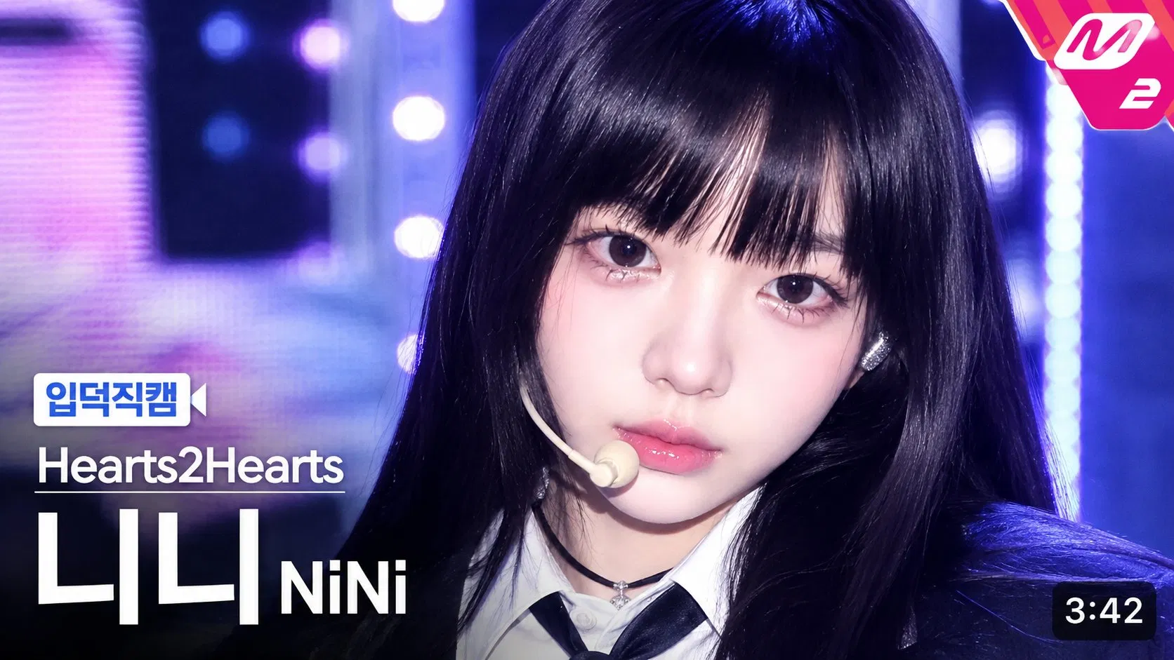 ChatGPT Image 2 K-pop 直拍縮圖 broadcast UI 模板 prompt 範例 — 真人 K-pop idol 版 Hearts2Hearts 니니（NiNi）입덕직캠，紫藍霓虹舞台燈泡牆、黑長髮、耳麥、白襯衫黑領帶制服風、右上 M2 紫紅角落徽章、左下입덕직캠白藍標籤、底部 3:42 時長框