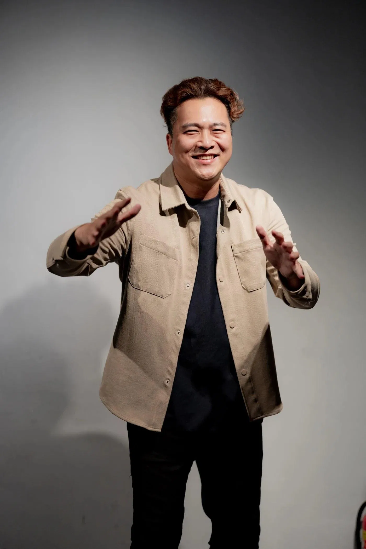 東區德穿卡其外套微笑，以雙手示意說話節奏