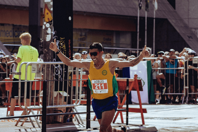 一張跑者突破 SUB 目標衝過終點線,高舉雙手慶祝的特寫照片。